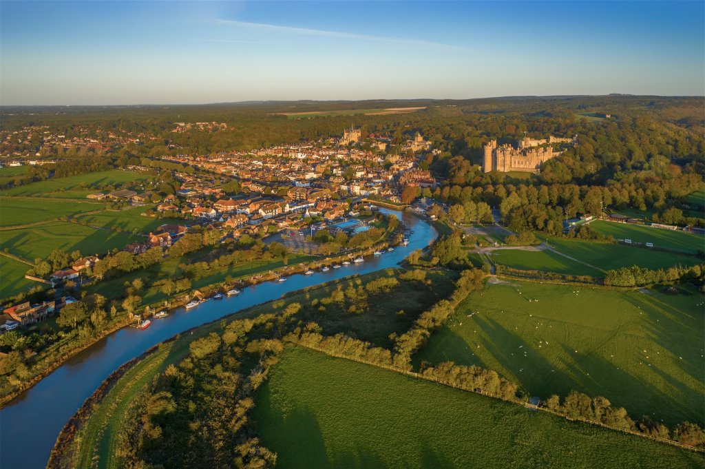 Arundel castle and town nestled around the river Arun at sunset.